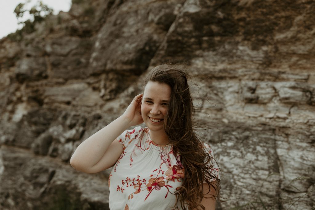 girl standing next to cliff in white dress
