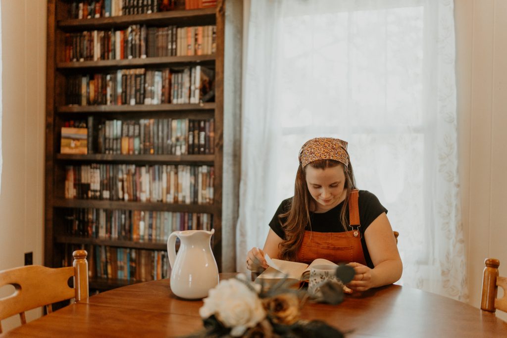 girl reading a book at table with bookshelf